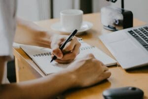 Left Handed Person taking notes at an Online Real Estate Investor Master Class at MAREI.